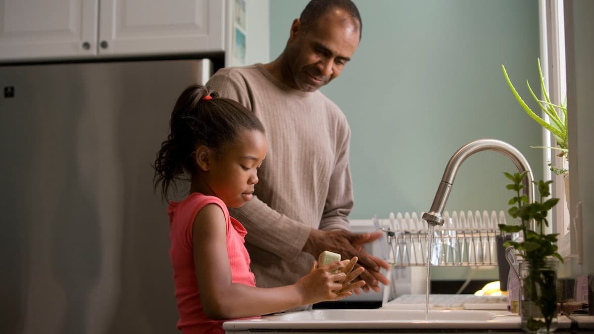 Padre enseñando a su hija a lavarse las manos.