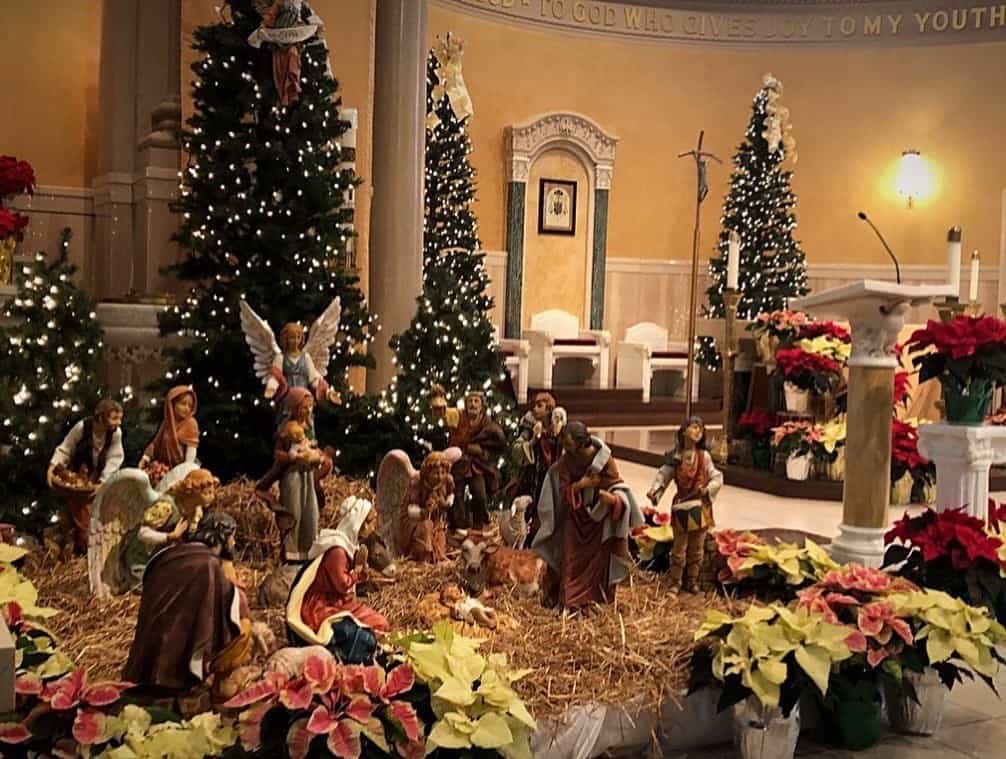 Un belén y un árbol de Navidad en una iglesia con decoración navideña