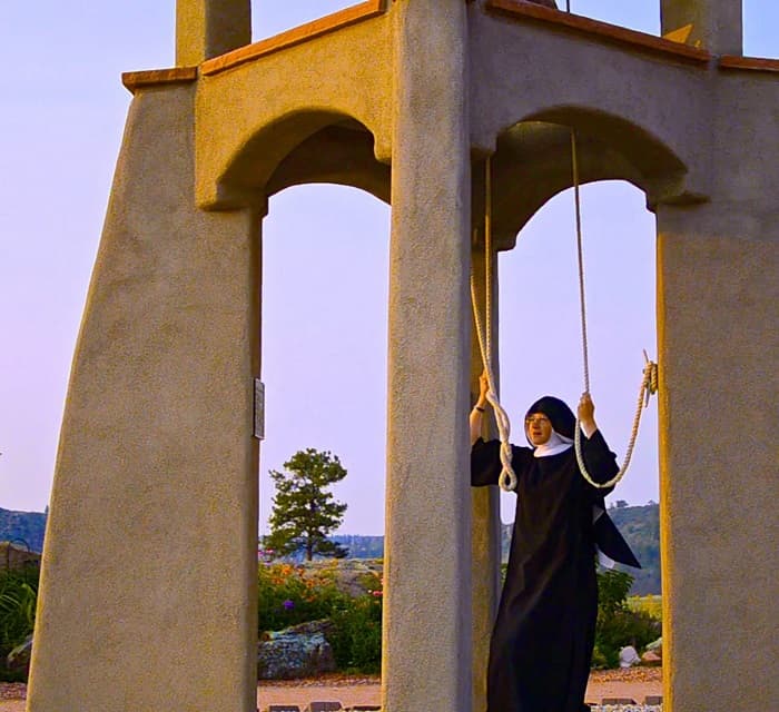Religiosa tocando las campanas de la abadía