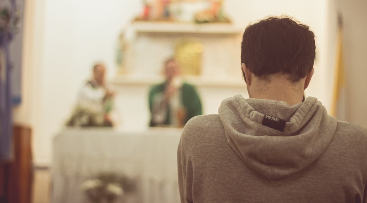 Joven arrodillado en misa