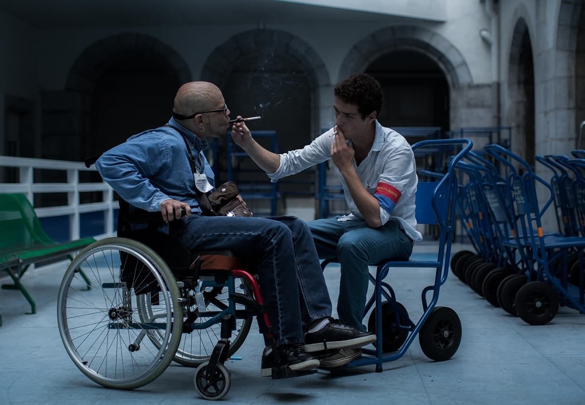 Un voluntario comparte un cigarrillo con un peregrino discapacitado en la película Lourdes