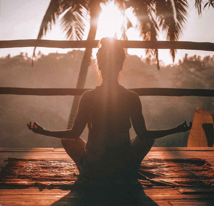 Mujer haciendo yoga frente al sol.