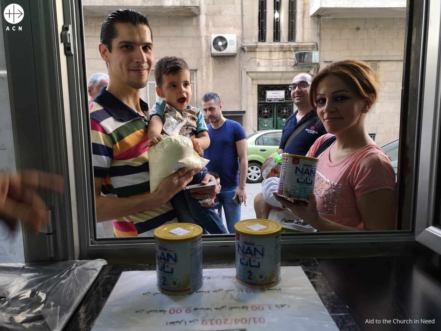 Una familia al recoger su paquete de alimentos de Una Gota de Leche en Alepo, Siria