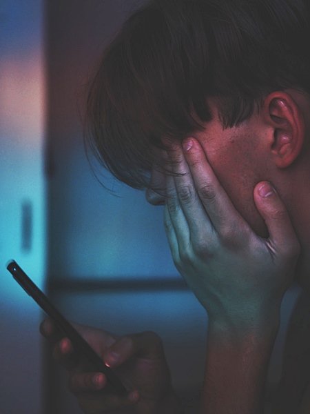 Adolescente deprimido mirando el móvil.