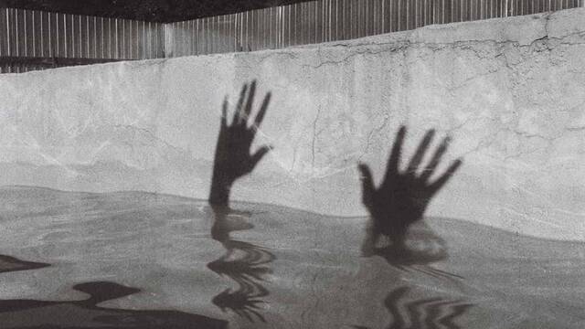 Sombra de unas manos en una piscina.