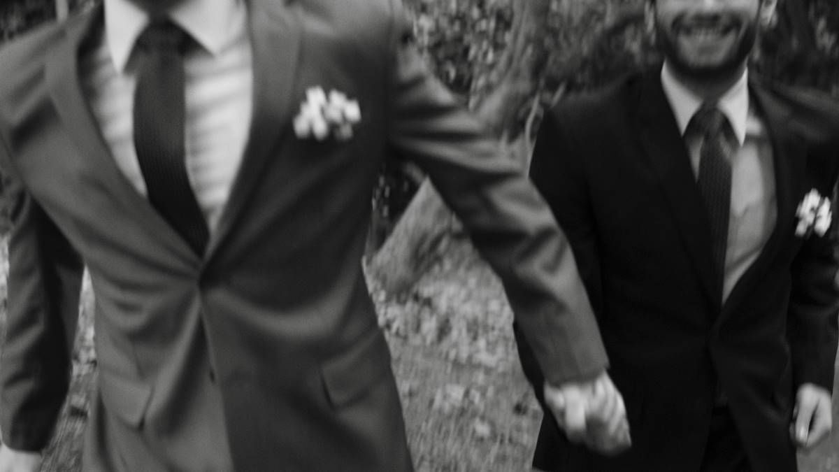 Dos hombres de la mano con traje de boda.