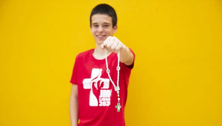 Un joven de la JMJ de Lisboa 2023 ofrece un rosario