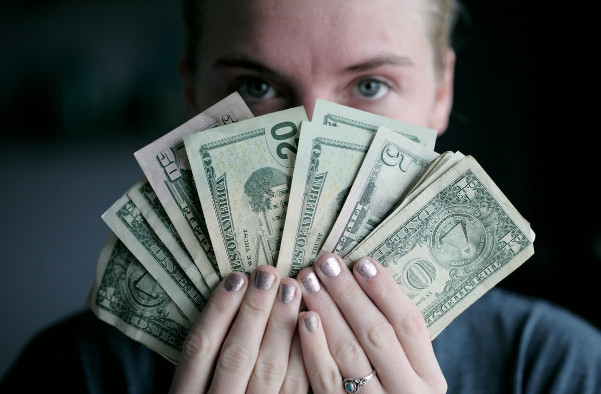 Un hombre oculta su rostro tras el dinero - foto de Alexander Grey para Unsplash