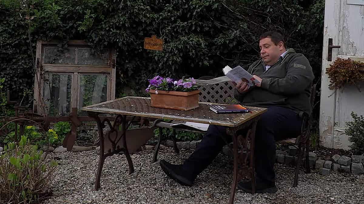 Wolfgang Ehrle leyendo un libro en un jardín.