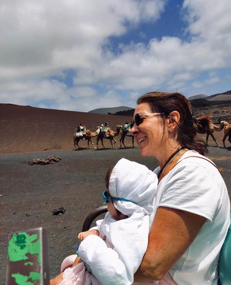 Luz, en brazos de su madre viendo unos camellos.