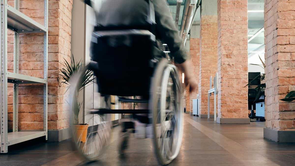 Una persona en silla de ruedas en un pasillo de un edificio.