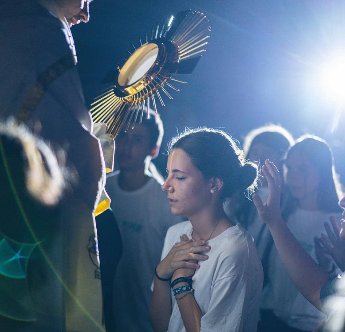 Una joven en adoración eucarística en un campamento de verano de LifeTeen