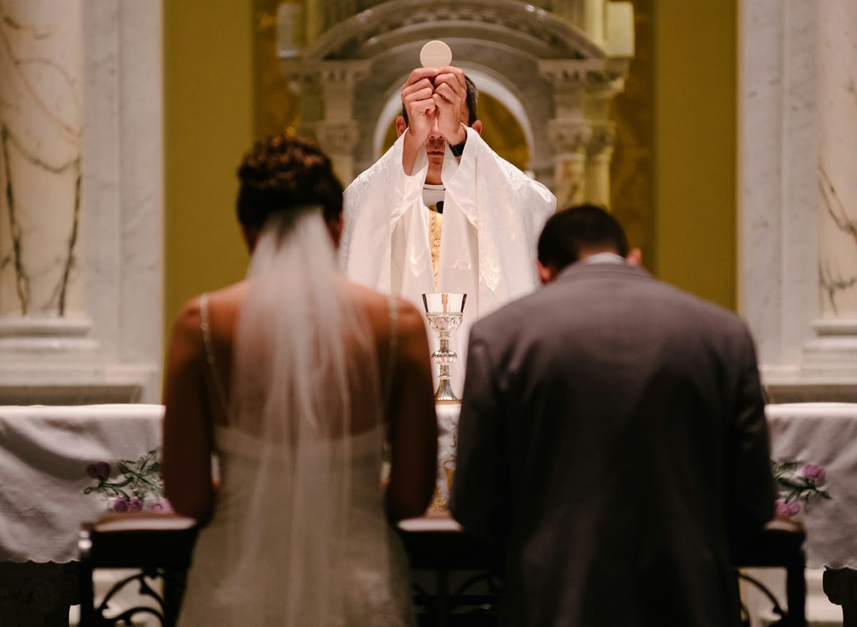 Novios de rodillas en una boda católica, foto de Josh Applegate en Unsplash