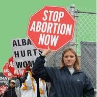 Una mujer levanta un carte que dice "stop al aborto ahora"