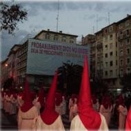 Una procesión religiosa con un cartel ofensivo a Dios al fondo
