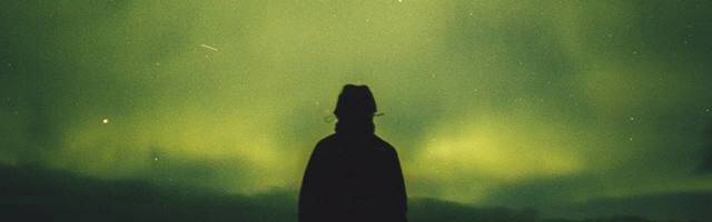 Sombra de un hombre contemplando la aurora boreal.