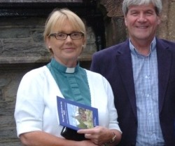 La reverenda Pat Storey con un feligrés, alzacuellos, camisa verde-irlandés y rebequita blanca