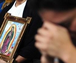 Una mujer reza a la Virgen de Guadalupe