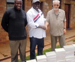 El padre Bernard Lesay con colaboradores de Action Batwa y unos libros y cuadernos para los niños del lugar