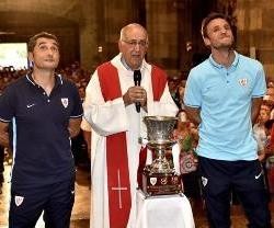 Gurpegui y Valverde con el párroco y la Supercopa ante la Virgen de Begoña