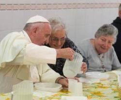 El Papa Francisco sirve el agua a una compañera de mesa en el comedor de Cáritas Florencia