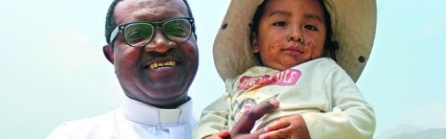 El padre Kameni, misionero camerunés en Perú, con un niño de Santa Eulalia, zona dañada por graves riadas la pasada primavera