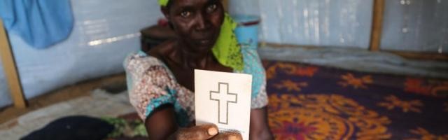 Godiya Ousman con su tarjeta-cartilla de bautismo - ha huido de Nigeria para salvar su vida y mantener su fe