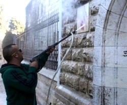 Limpiando las pintadas anticristianas en la entrada de la Basílica de la Dormición de la Virgen en Jerusalén