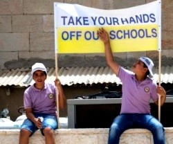 Dos jóvenes alumnos de las escuelas cristianas de Tierra Santa con una pancarta reivindicativa - Israel no está pagando lo comprometido