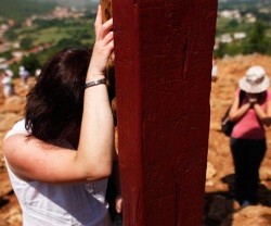 Una mujer en oración en la cruz de la Colina de las Apariciones de Medjugorje
