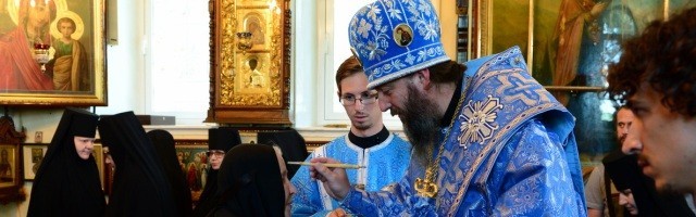 En la fiesta del icono de Kazán, un obispo ortodoxo bendice con un pincel en agua bendita a unas religiosas - a la izquierda, el icono preside la ceremonia