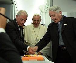 El padre Federico Lombardi (a la derecha) fue homenajeado con una tarta durante el vuelo de regreso de Cracovia, su último servicio como portavoz de la Santa Sede.