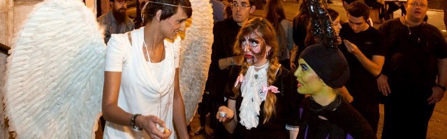 Night Fever en noche de Halloween en Valencia - Una evangelizadora vestida de ángel invita a orar con velitas en la iglesia a jóvenes vestidos de zombis