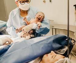 Mujer que acaba de dar a luz mira al hijo que le enseña la enfermera.