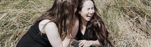 Dos mujeres jóvenes ríen mientras cotillean.