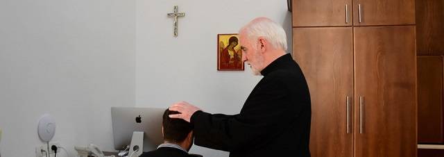 El padre Mcdonagh, exorcista del Patriarcado Latino de Jerusalén, impone las manos a un joven