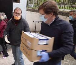 El alcalde de Madrid visita una parroquia y forma parte de una cadena humana para repartir alimentos