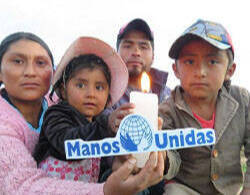 Niños sudamericanos con una vela y el cartel de manos Unidas