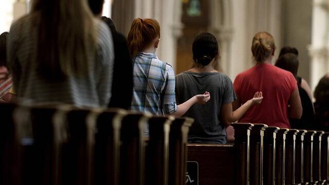 Un grupo de jóvenes reza en una iglesia