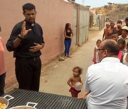 El padre Robinson, en la imagen bendiciendo una comida para las personas pobres que hacen cola