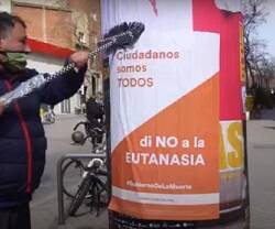 Hombre pegando un cartel de Vividores contra la eutanasia