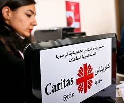 Una colaboradora junto a una caja de ayuda de Cáritas Siria