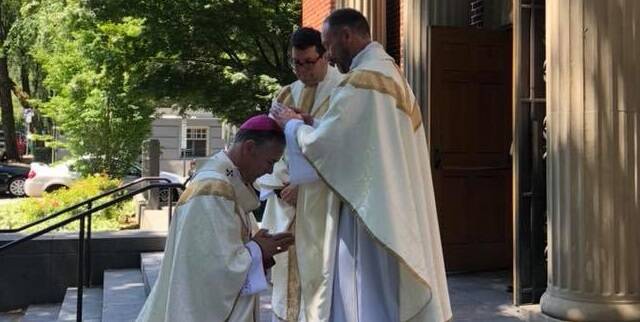 Brent Crowe bendice al arzobispo Sample en 2018, tras ser ordenado sacerdote