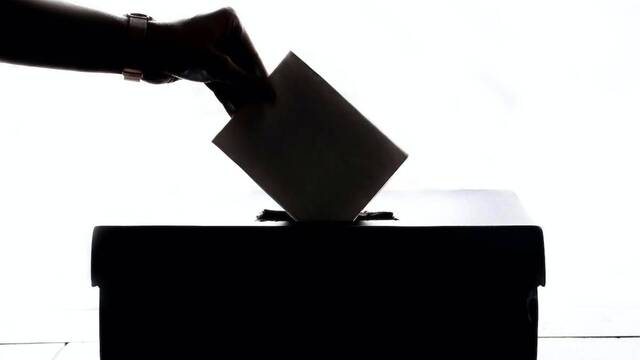 Una mano votando en una urna.