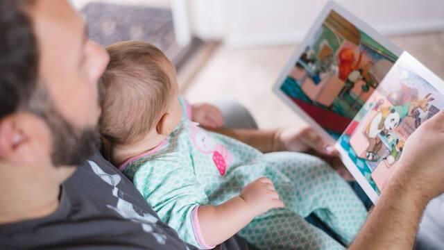 Un padre muestra un libro a su bebé.