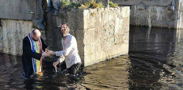 Un sacerdote ortodoxo rumano bautiza en un río irlandés al escrito inglés Paul Kingsnorth en 2021