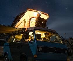 Un hombre mira al cielo estrellado desde el techo de su furgoneta