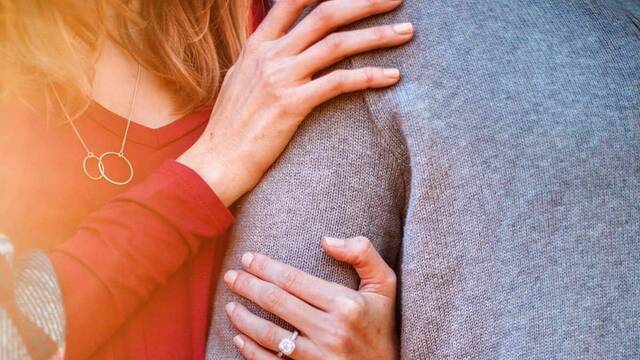 Una mujer abraza el brazo de un hombre.
