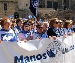 Voluntarios de  Manos Unidas con pancarta y logo en Santiago de Compostela