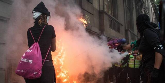 Incendio provocado en una marcha de feministas abortistas en México  - unas encapuchadas echan un chorrito de agua, quizá arrepentidas